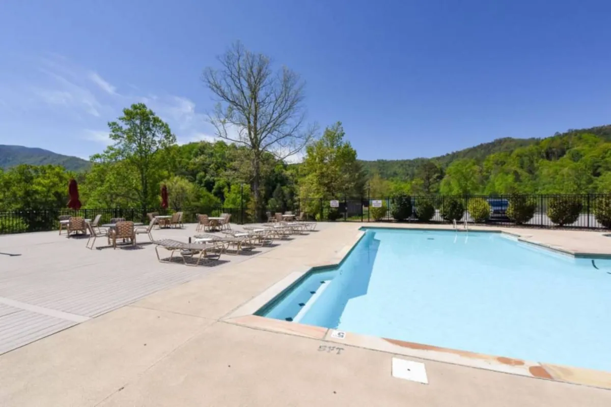 A sparkling swimming pool surrounded by deck chairs with distant mountain views, set up for sunbathing, swimming, and relaxing social gatherings. The setting is bright and inviting, perfect for leisure after a day’s adventure.